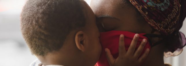 Mom embraces toddler through pandemic mask