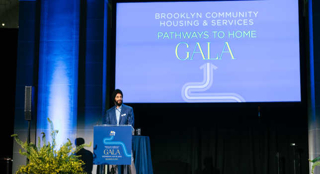 Surinder Singh proudly stands at a podium in front of a screen that says Brooklyn Community Housing & Services Pathways to Home Gala