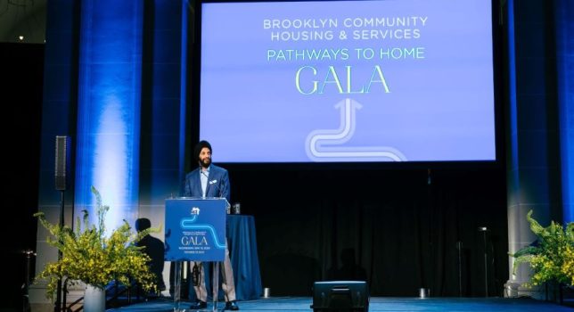 Surinder Singh stands at a podium in front of a screen that says Brooklyn Community Housing & Services Pathways to Home Gala