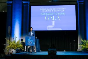Surinder Singh stands at a podium in front of a screen that says Brooklyn Community Housing & Services Pathways to Home Gala